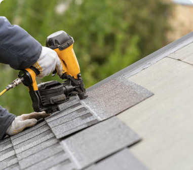 Roofing contractor nailing shingle on roof using a nail gun.